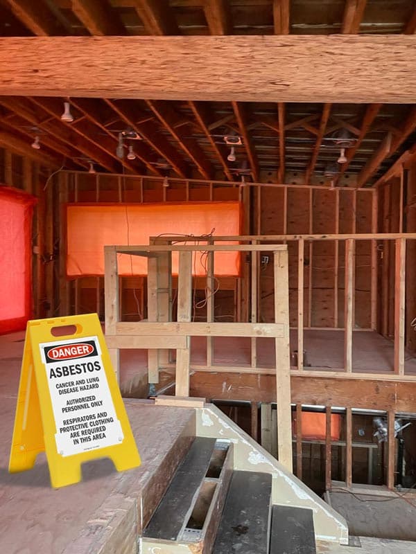 An asbestos work area sealed with containment sheeting and warning signage